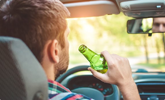 A man drinking from a bottle in a car - John Abel Law Office