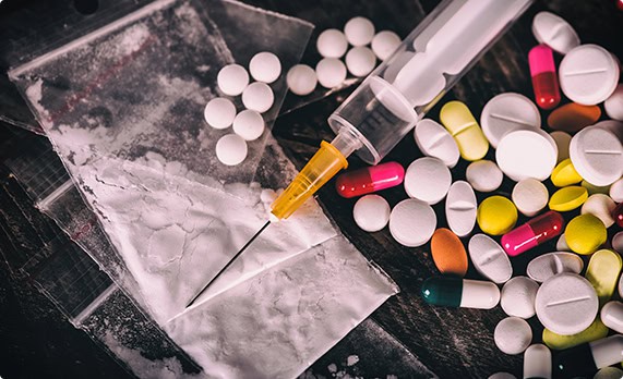 Assorted drugs and pills spread out on a tabletop - John Abel Law Office