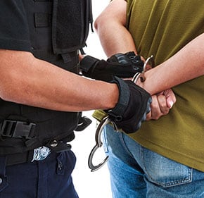 Police officers in handcuffs being held by a person - John Abel Law Office